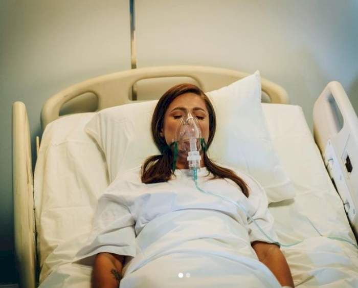 raluka baniciu pe un pat de spital cu masca de oxigen la gura