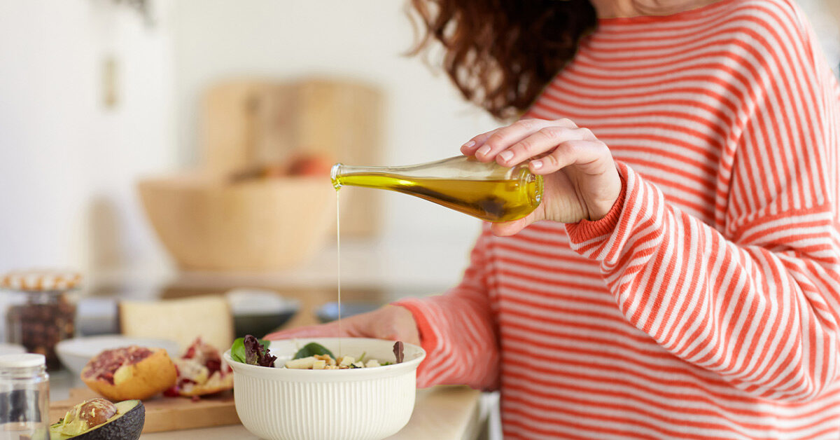 femeie care toarnă ulei de măsline în salată
