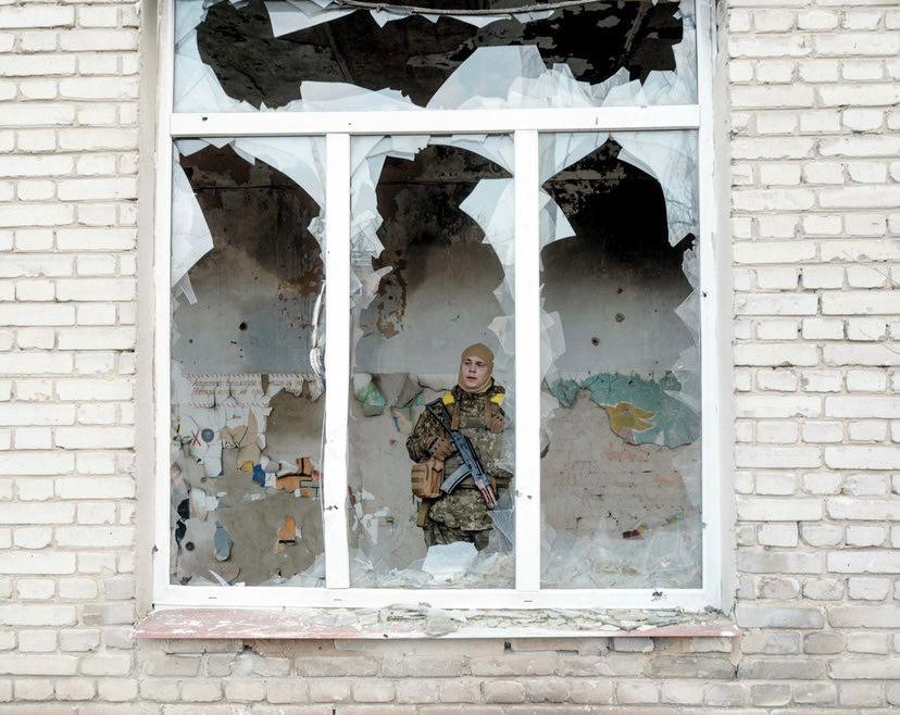 un soldat care priveste spre un geam distrus