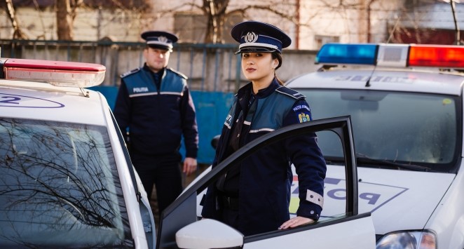femeie si barbat politisti langa autospeciale