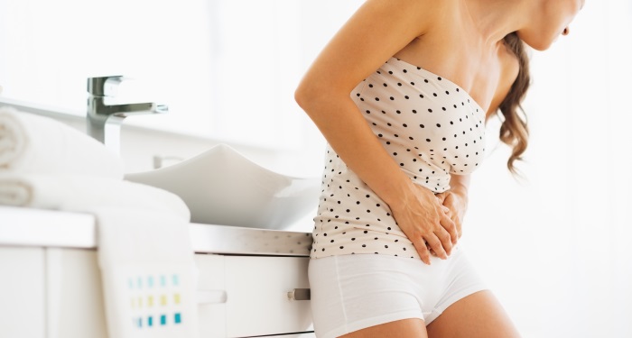 femeie care se tine de abdomen din cauza infectiei urinare