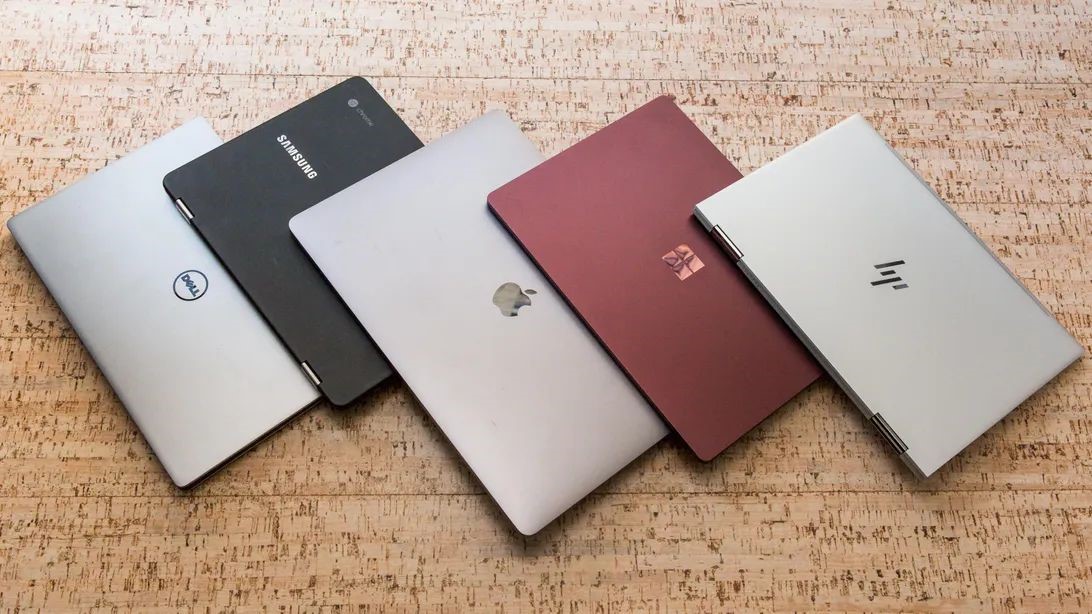cinci laptop-uri pe o masa de lemn