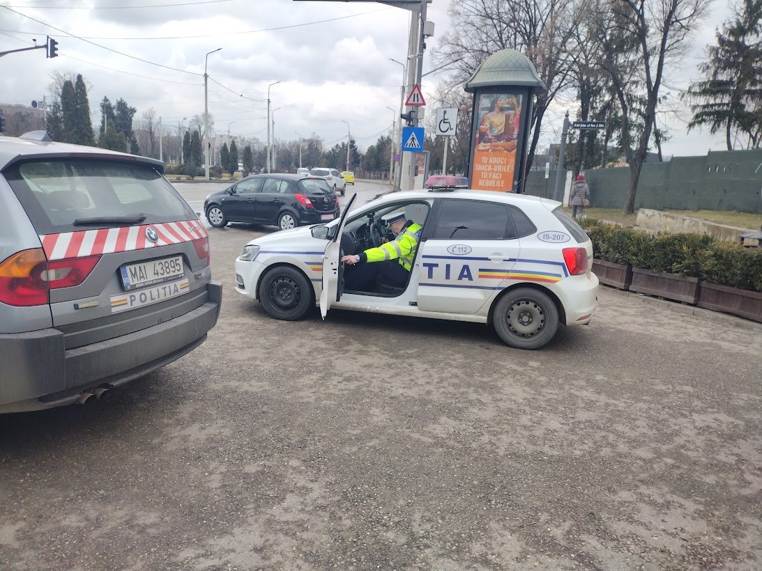 Un agent inchide portiera unei autospeciale de Politie; in fundal, un alt vehicul inscriptionat „Politia”