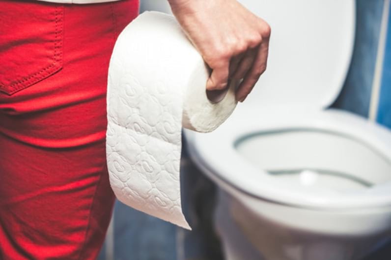 o persoană cu pantaloni roșii cu o hârtie igienică în mână