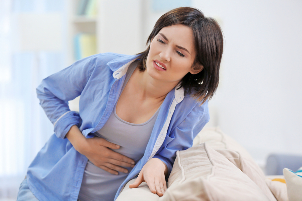 femeie care se tine de abdomen din cauza durerilor provocate de pancreas