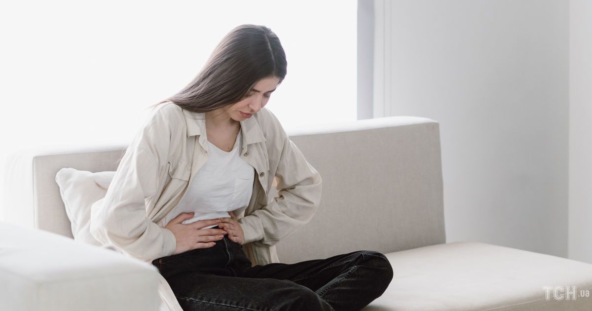 femeie care sta asezata pe pat si se tine de abdomen din cauza durerilor provocate de pancreas