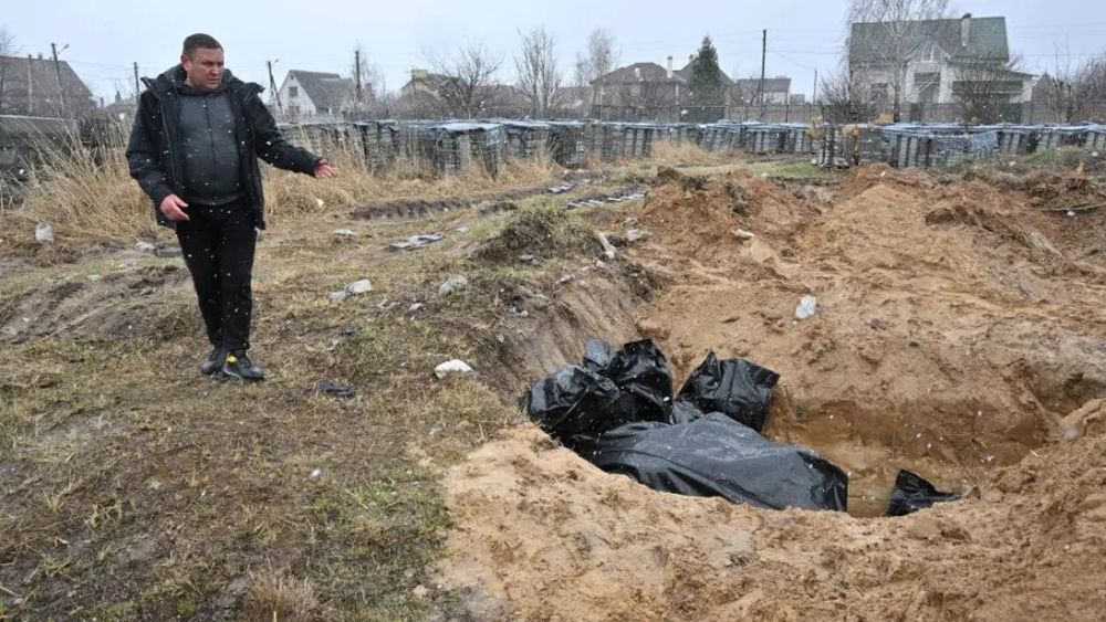 ruşii au comis masacrul de la Bucea, barbat ce indica faptul ca trupurile oamenilor morti sunt aruncati intr-o groapa comuna