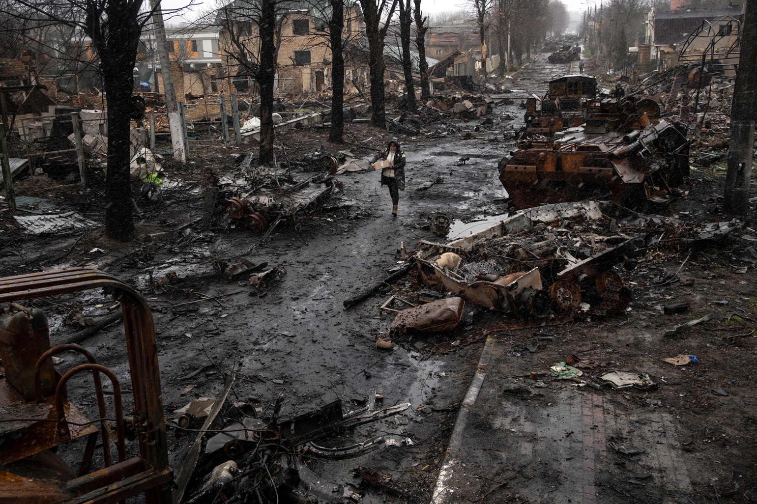 ruşii au comis masacrul de la Bucea, femeie ce merge printre masini distruse de bombardamentele rusilor la Bucea Ucraina