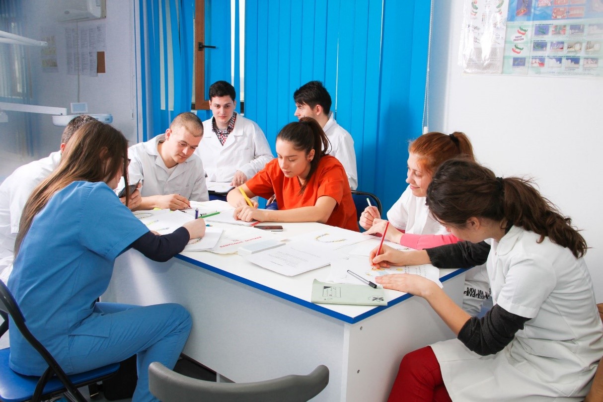 studenti in halat alb care studiaza la o masa