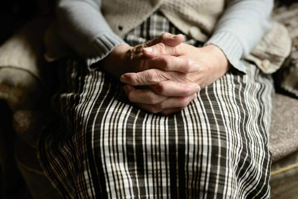 o femeie în vârstă care ține mâinile împreunate