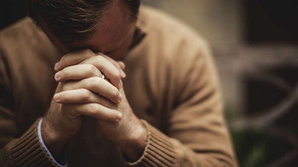 un bărbat în pulover crem care se roagă