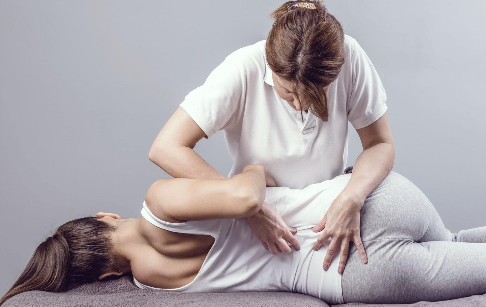 femeie care efectueaza un masaj de reabilitare unei alte femei din cauza unui nerv sciatic blocat