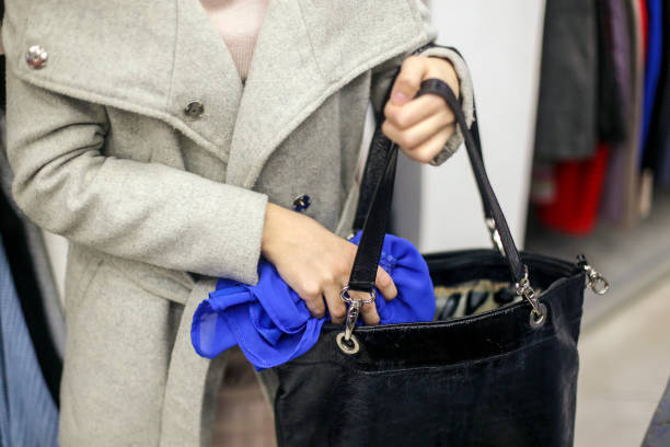 o femeie care pune un articol vestimentar in geanta