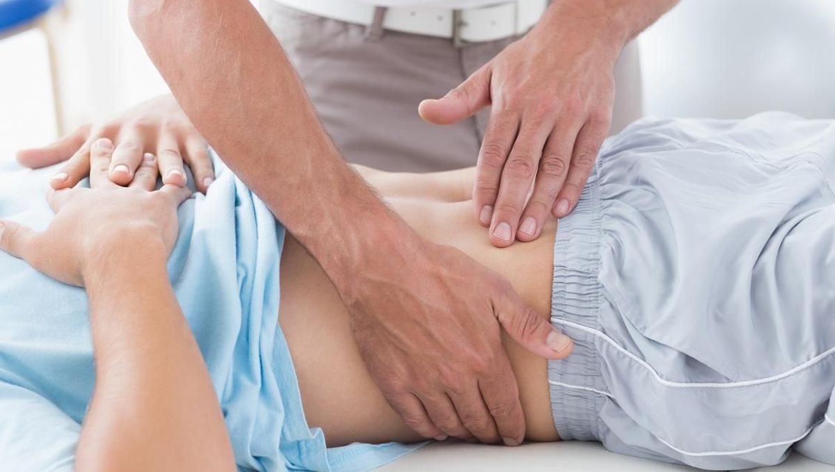 medic care verifica abdomenul unei femei pentru a identifica o hernie inghinala