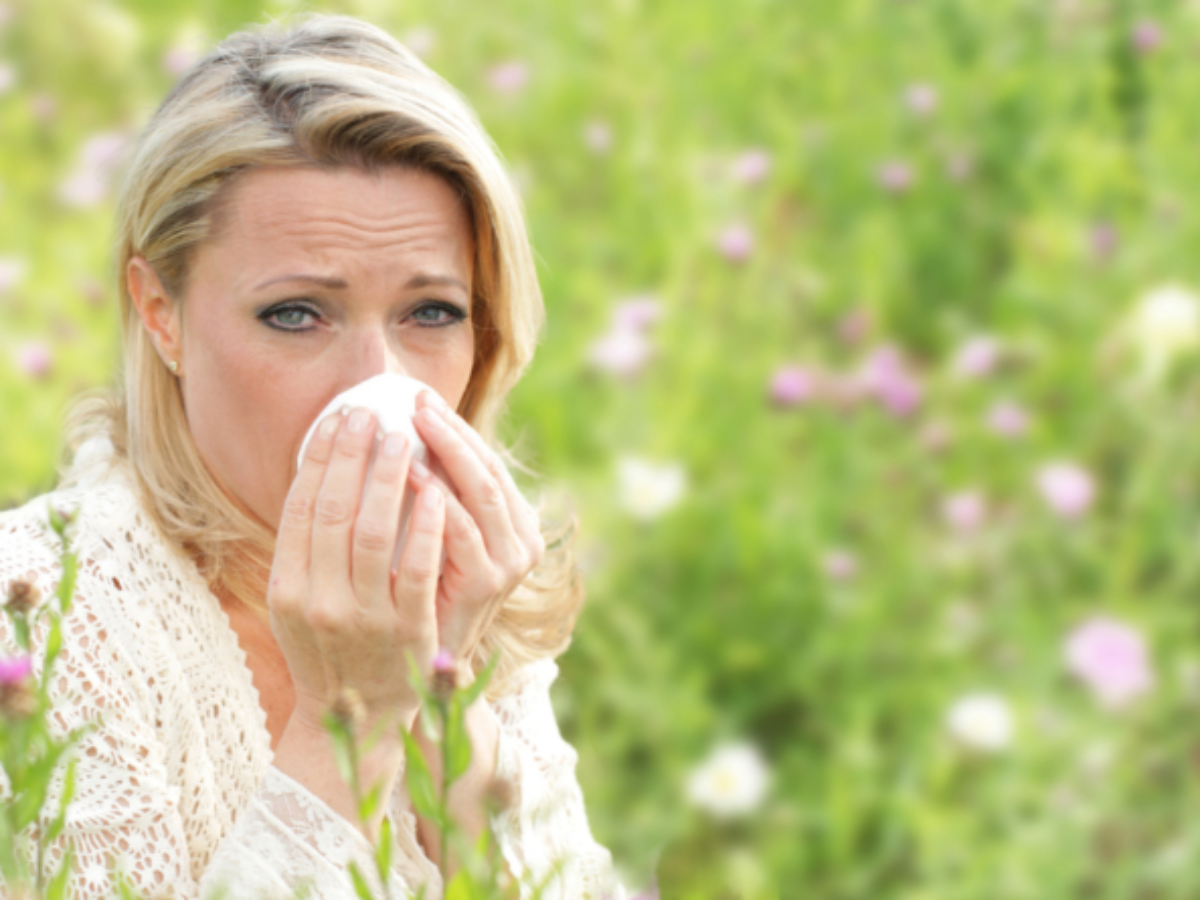 femeie care isi sterge nasul din cauza unei alergii stang int-un lan