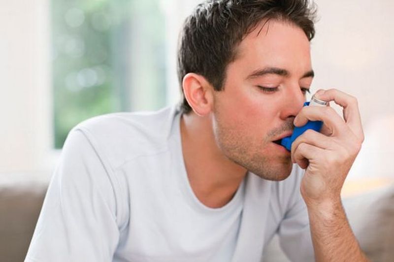 un bărbaqt cu astm bronșic care folosește un inhalator