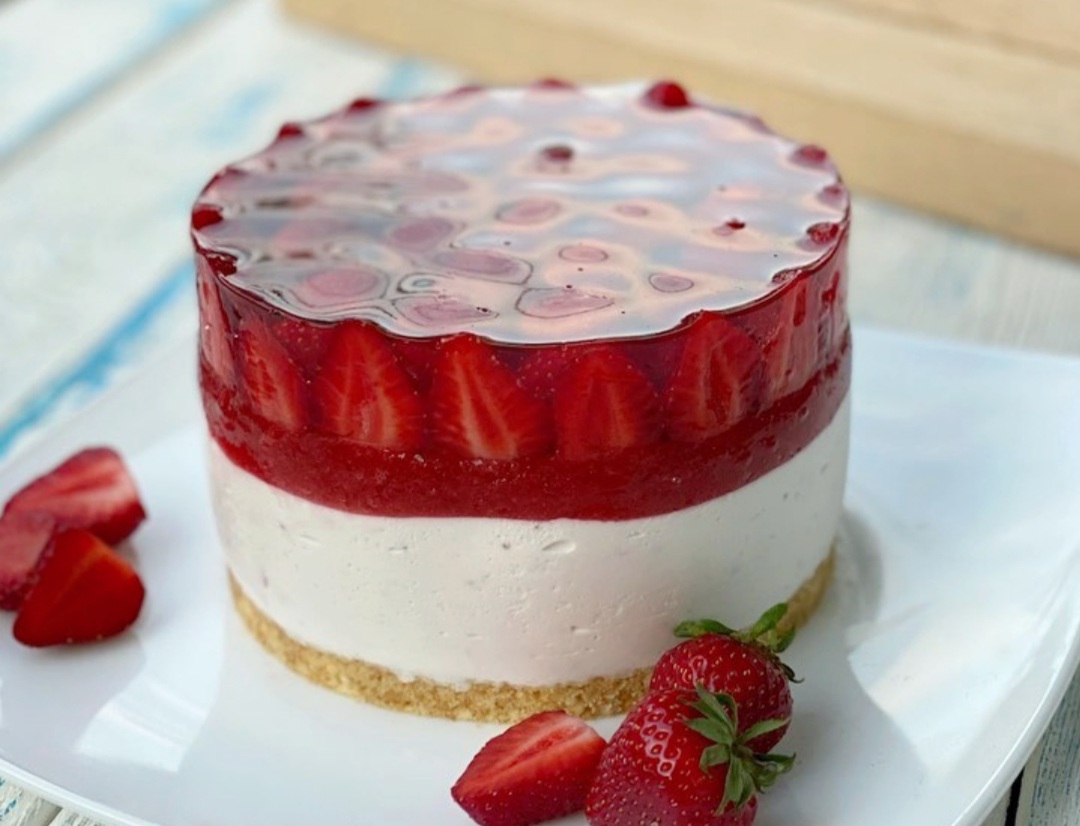 un cheesecake fara coacere cu mascarpone decorat cu capsuni pe o farfurie