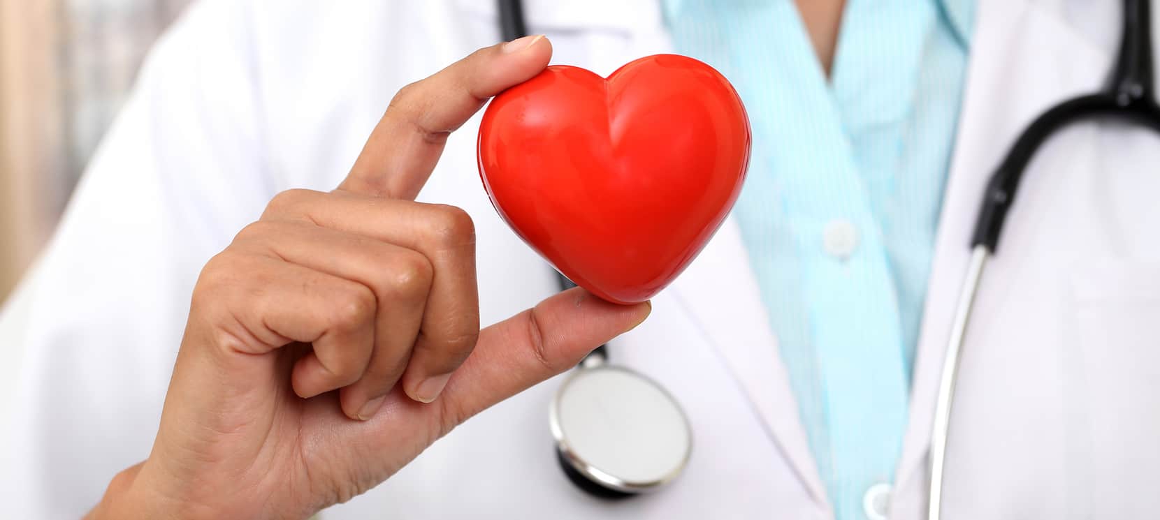 un medic care ține în mână o inimă roșie din plastic
