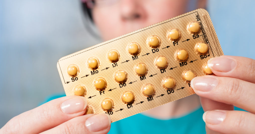 femeie care tine un blister cu pastile contraceptive in mana