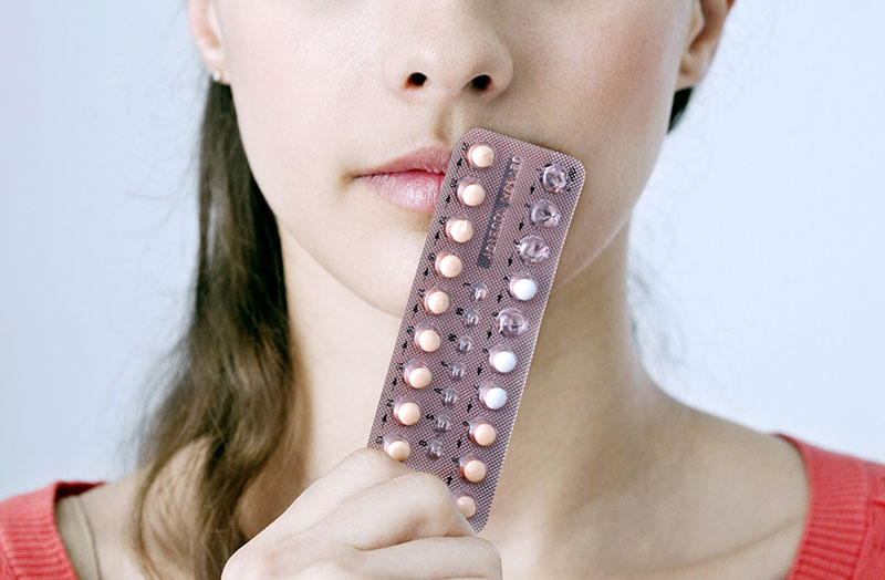 femeie care tine un blister cu pastile contraceptive in mana