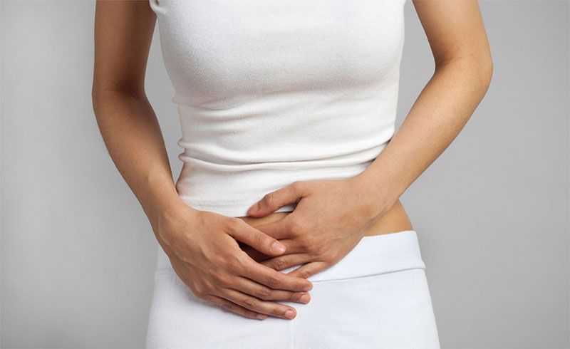 femeie care se tine de abdomen din cauza incontinentei urinare