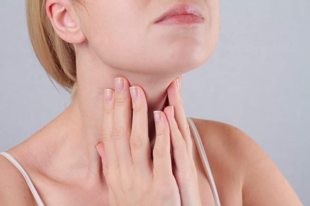 femeie care se tine de gat din cauza problemelor cu tiroida
