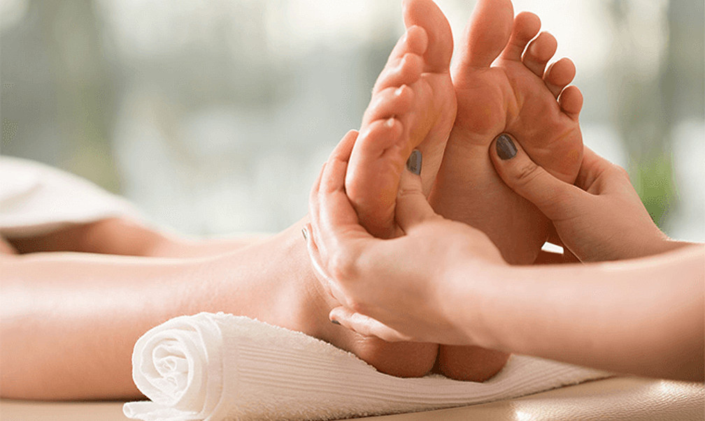 femeie care face masaj a picioarelor unei persoane