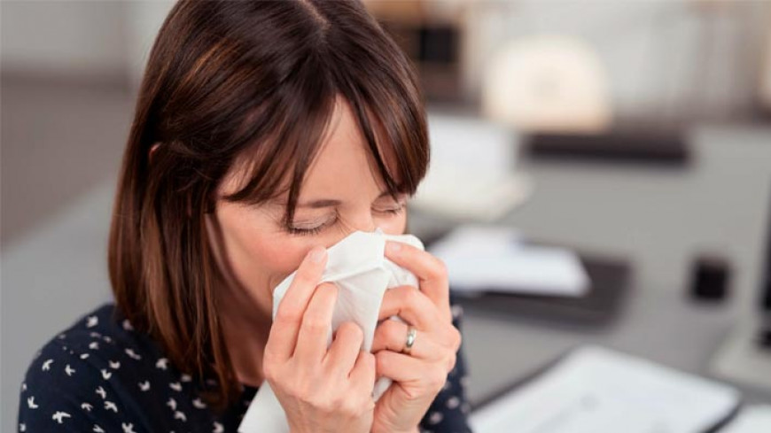 femeie care isi sufla nasul din cauza sinuzitei