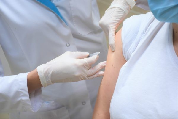 un medic care vaccineaza o persoana