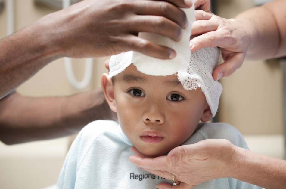 medic care bandajeaza capul unui copil