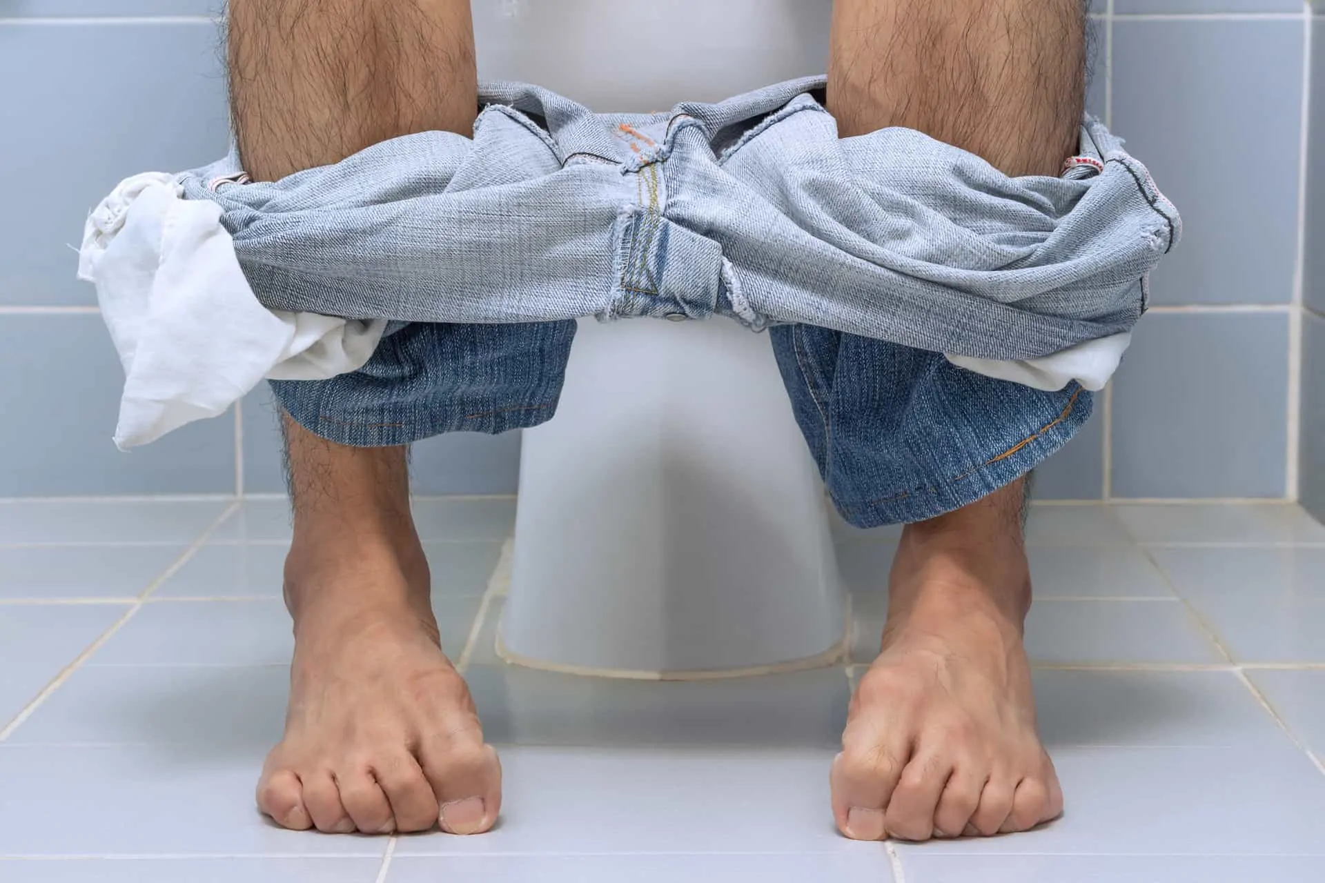 picioarele unui barbat care sta asezat pe o toaleta