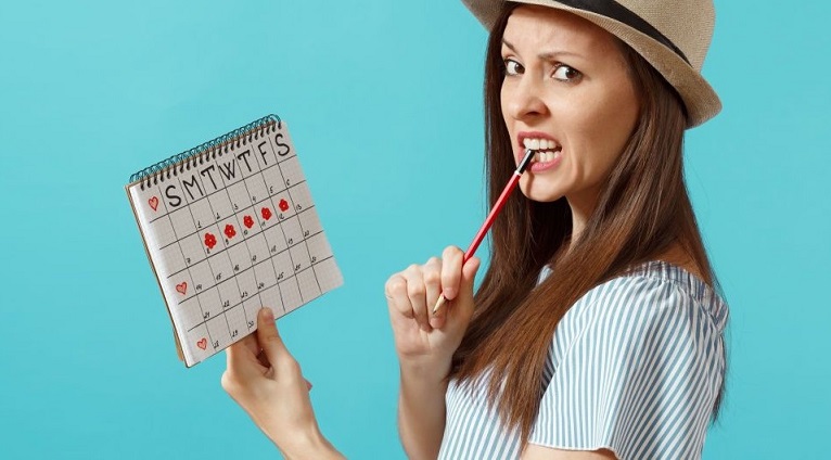 femeie care tine un calendar in mana si un creion in gura